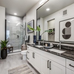 Maximize your storage space with custom white cabinetry and expansive countertops. bathroom with a large mirror